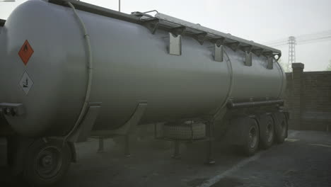 large industrial tanker truck parked in a foggy environment near a brick wall