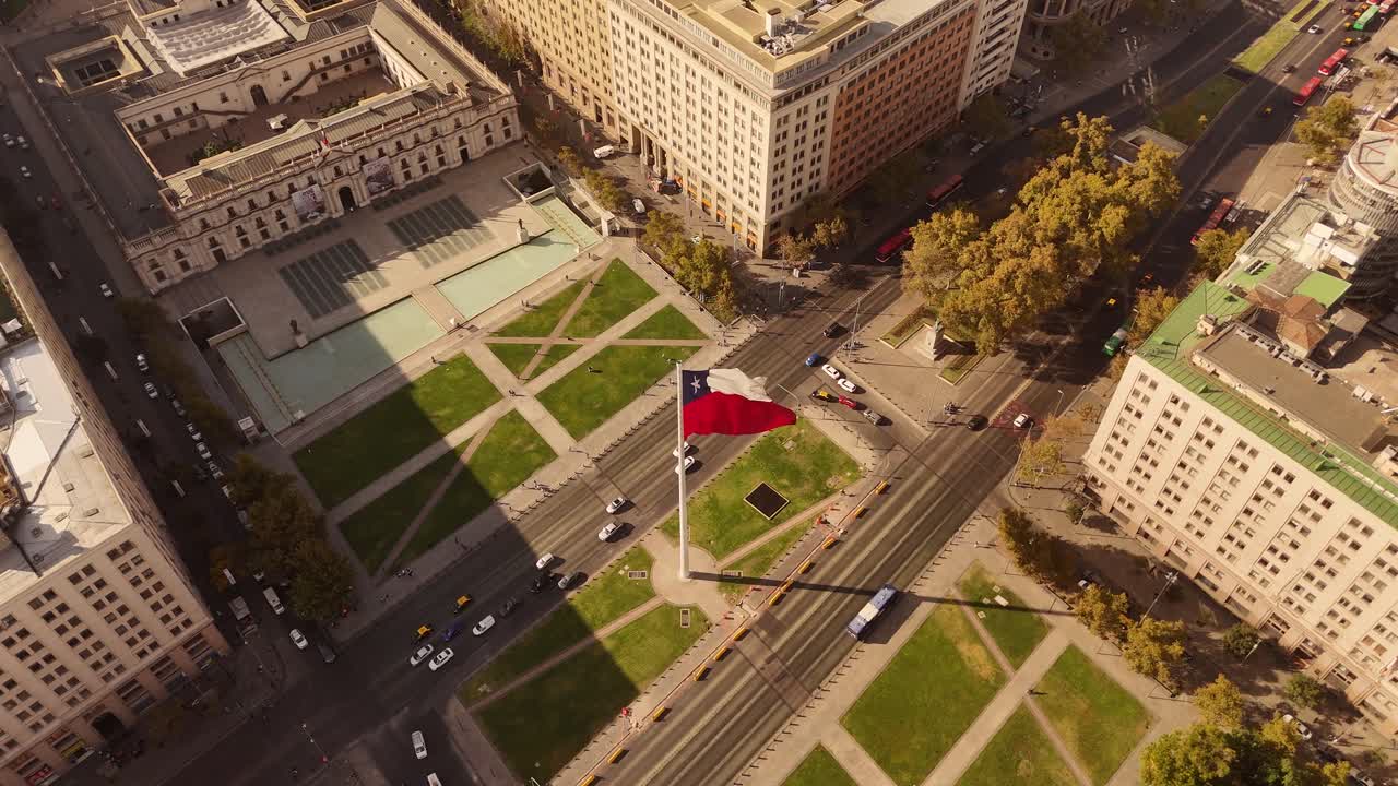 Chilean flag waving in the avenue with city traffic in de Chile. Aerial top down shot. Bus and cars with tram on street.