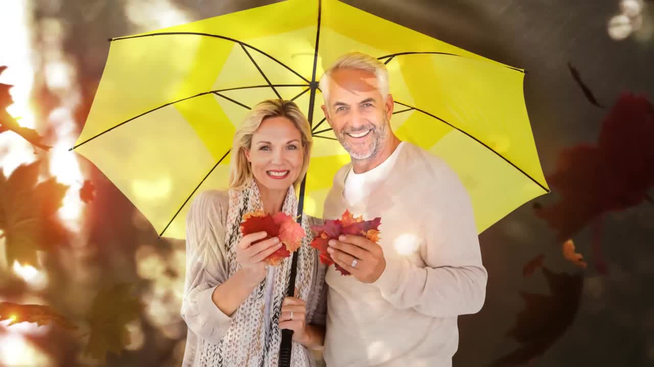 pareja mayor con hojas de otoño de pie con paraguas amarillo en el bosque de otoño 4k