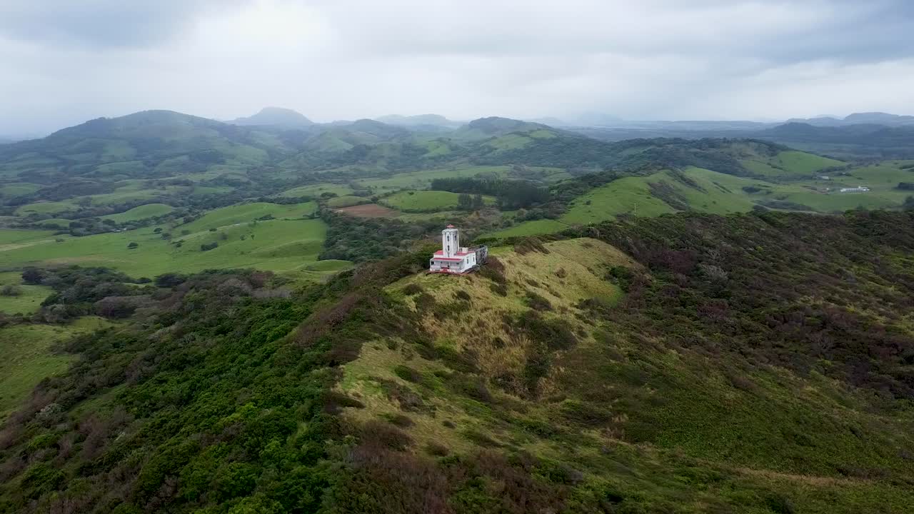 aerial del faro de roca parte en la hermosa colina verde