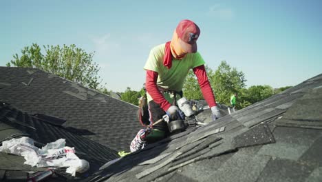 trabajador de la construcción usando pistola de clavos para instalar nuevas tejas de techo en una casa en cámara lenta