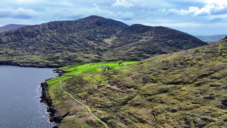 Drone-static-remote-road-and-farmstead-under-mountain,Cods-head-West-Cork-Ireland