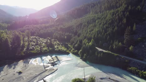 Aerial-Drone-Valley-Landscape-Pushing-Shot-of-Soo-River-and-Trees-and-Mountain-Background-with-Sun-Flare-Canada-4K