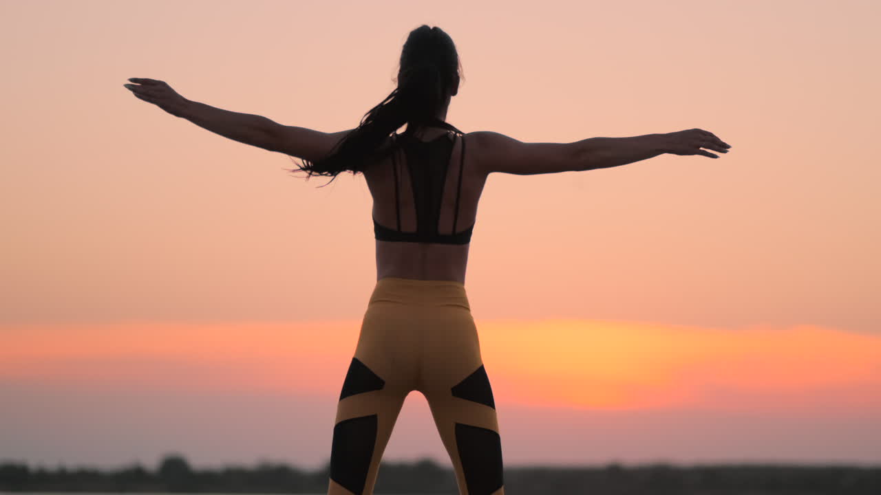 mujer de fitness feliz haciendo saltos o ejercicios de salto de estrellas en la orilla del mar al aire libre copia el espacio. niña trabajando en la playa en la mañana de verano retrato de longitud completa. concepto de estilo de vida saludable