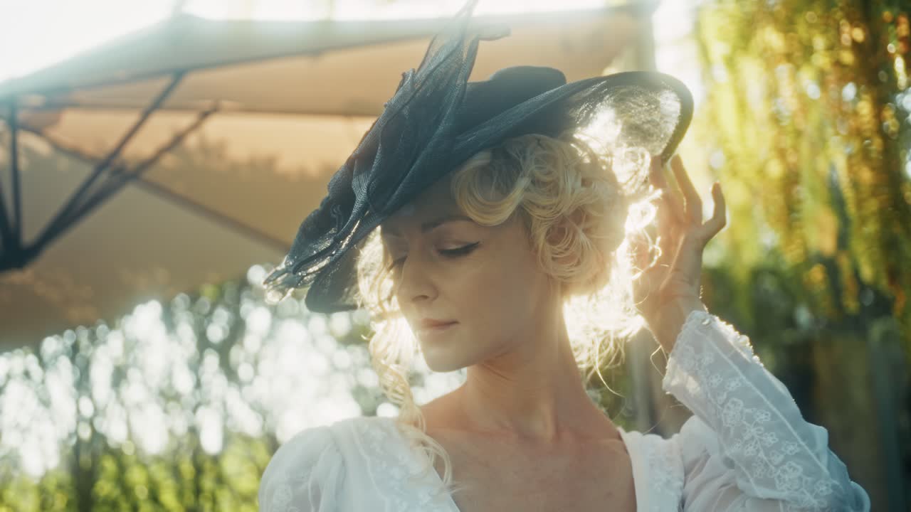 Donna elegante con cappello vintage che posa all'aperto con riverbero solare