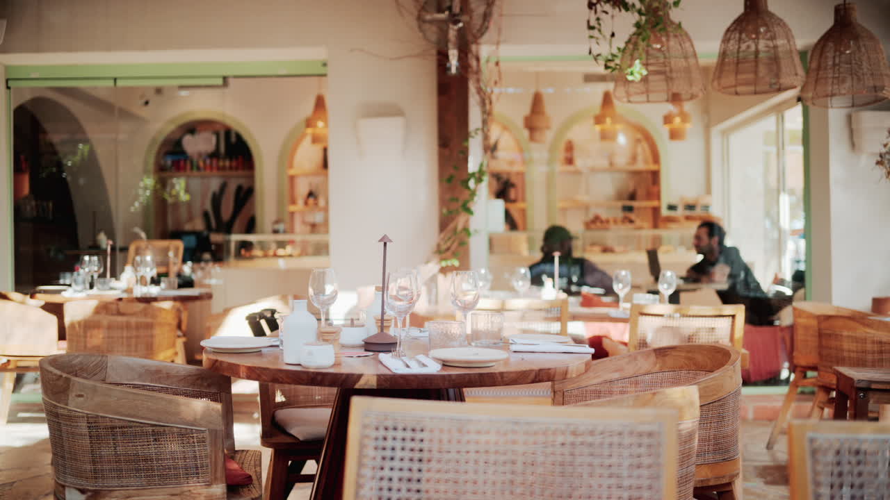 Warm and elegant restaurant interior with wooden chairs, wine glasses, and natural light
