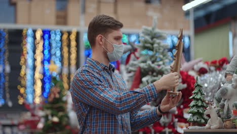 compras en pandemia y cuarentena. un hombre con una máscara protectora en una joyería y guirnaldas con juguetes para árboles de navidad y en casa. guirnaldas navideñas y decoración.