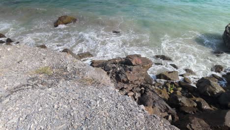 a beach landscape from a hillside overlooking the caribbean sea, where waves crash against the rocks.