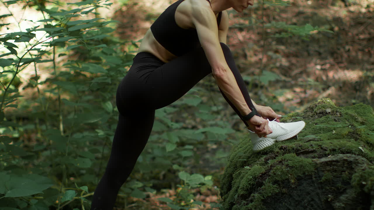 Woman Tying Shoelaces During Outdoor Exercise in a Forest