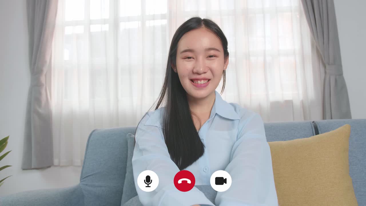 Donna asiatica che parla alla telecamera nel soggiorno di casa, video in 4K