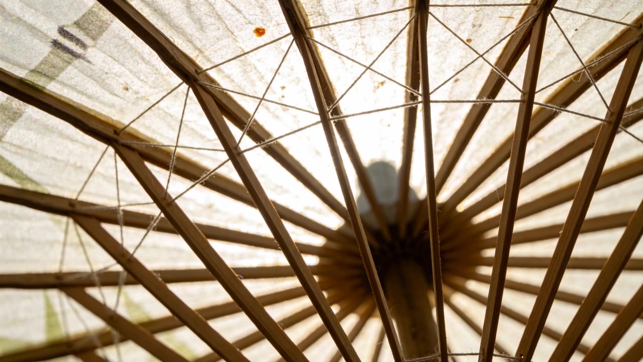 Swaying paper parasol underside showing shifting shadow over stain at patio, breeze rustling ribs