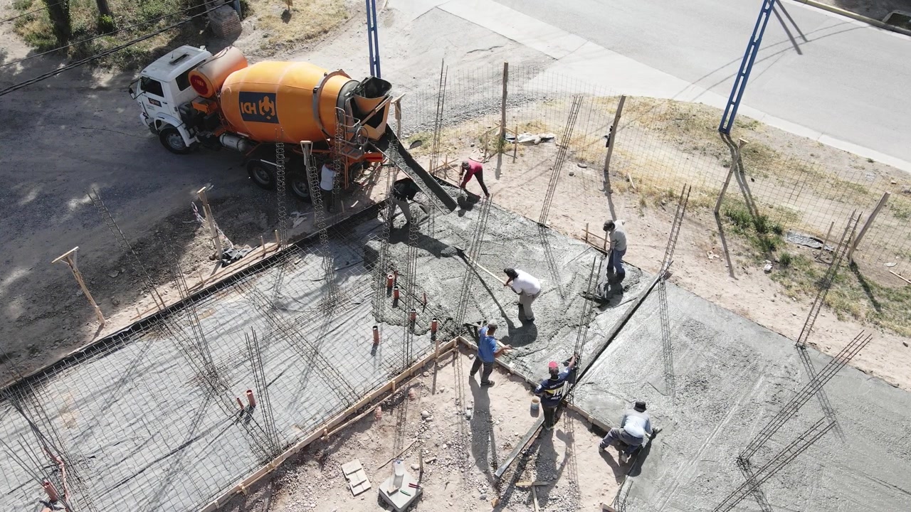 Workers process fresh concrete from a concrete track on the construction of a new building, General Roca - static aerial shot