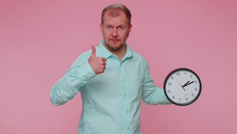 joven barbudo mostrando el tiempo en el reloj, ok, pulgar arriba, aprobar, señalando con el dedo a la cámara