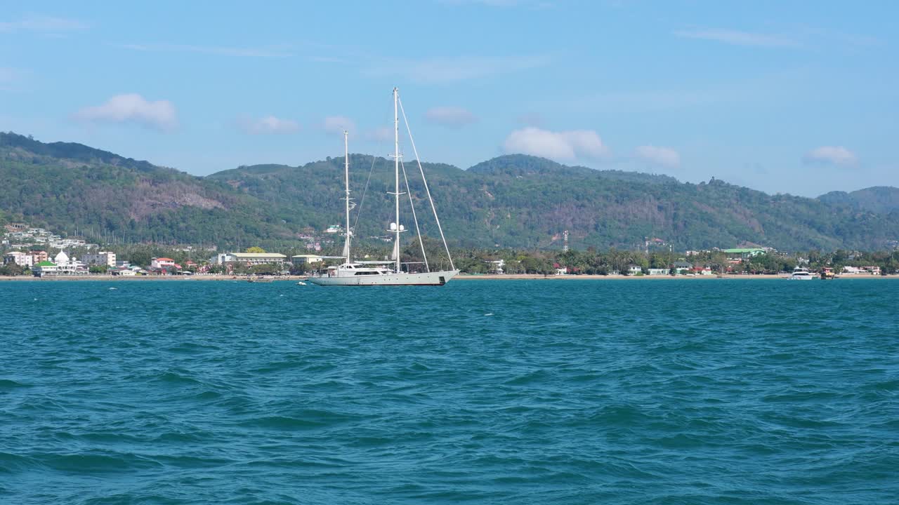A serene view of a sailboat and fishing boat on the ocean near Ko Racha Yai, Phuket, under clear skies