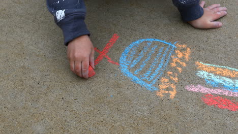 young boy age 4 years old, drawing on sidewalk with chalk