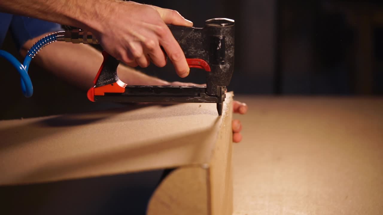 usando una pistola de clavos para montar piezas de madera