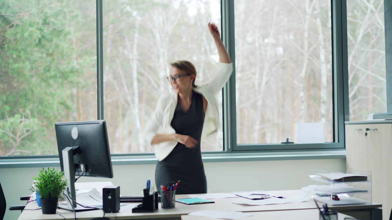 Donna d'affari felice che balla in ufficio