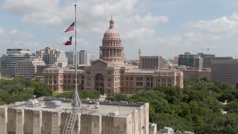 rising wide aerial of austin, texas state capitol building at midday with clouds, bright sunlight, and the ut tower in the background