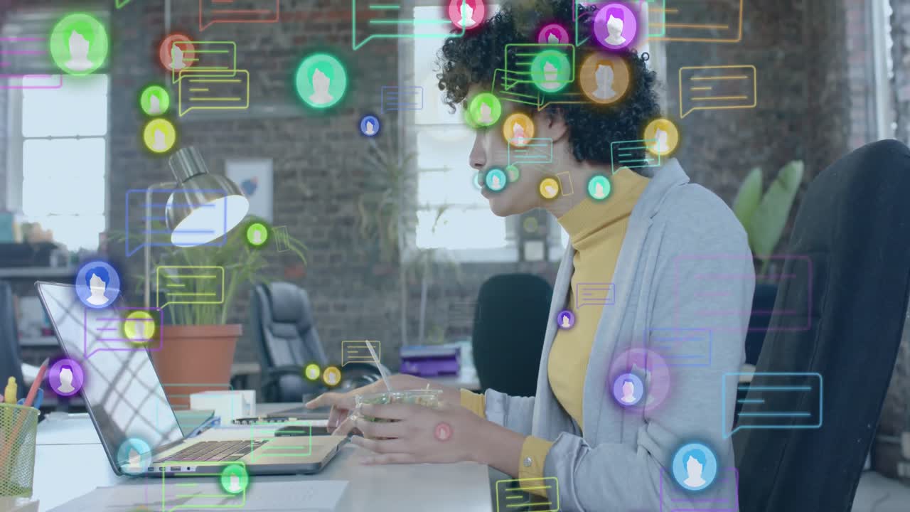 animación de iconos de los medios sobre una mujer de negocios biracial usando una computadora portátil y almorzando en la oficina
