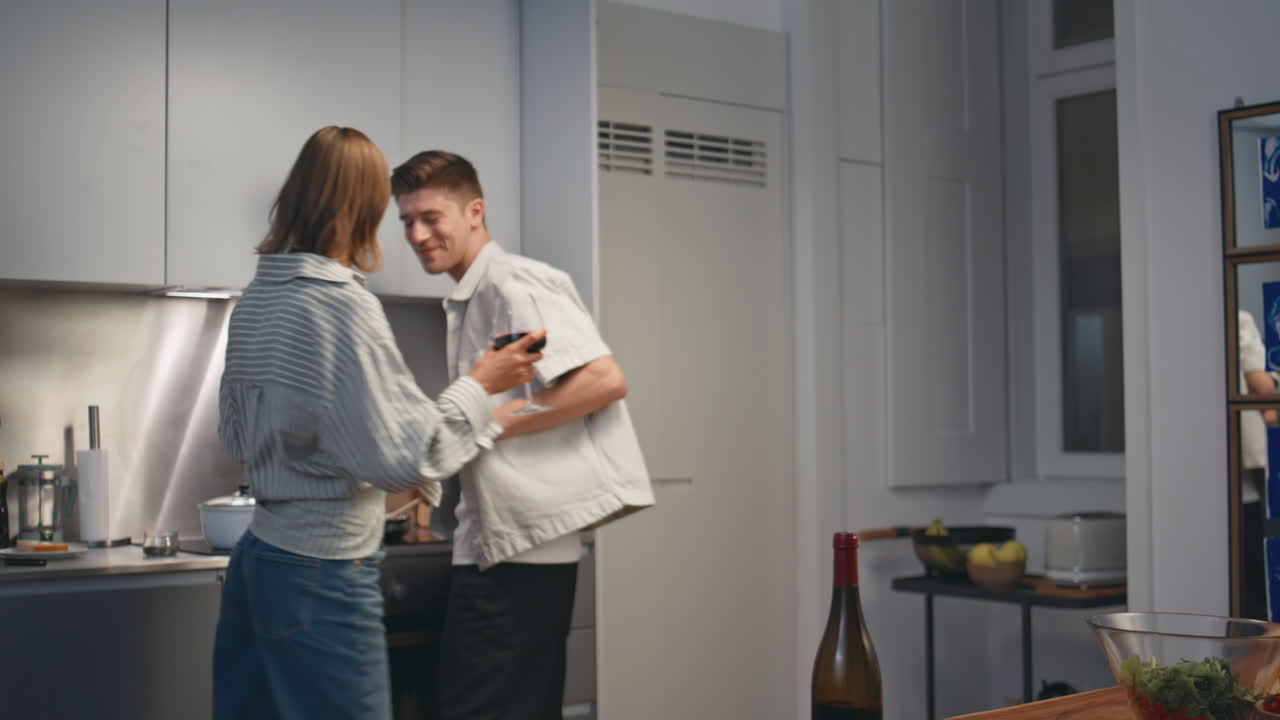 Happy couple tasting wine in home kitchen. Smiling sweethearts cooking romantic