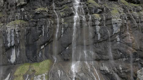 vuelo cercano de acantilados verticales salpicados de agua derretida que baja por la montaña
