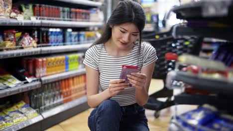 and-Asian-girl-visitor-chooses-one-of-two-products.-Happy-shot-visitor.-Choice-of-products-in-the-store