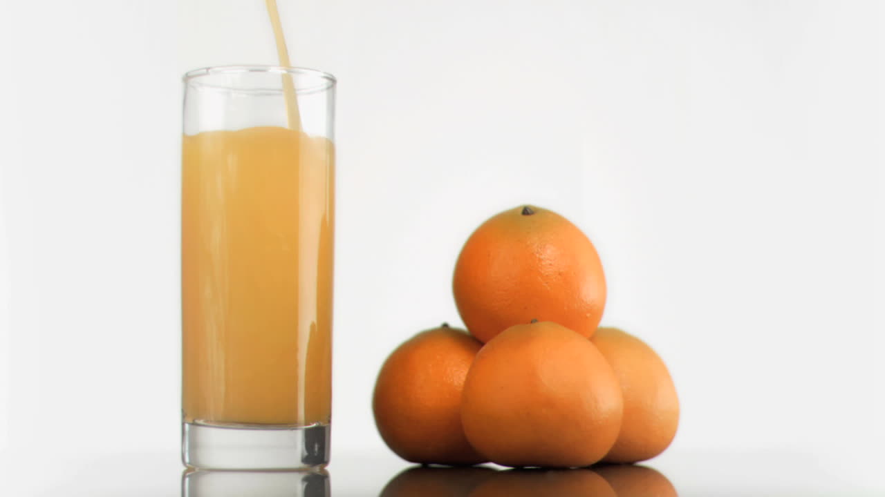 Succo d'arancia al rallentatore che riempie un bicchiere
