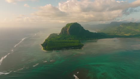 scenic landscape wild nature tropical island with rocky mountains overgrown dense green jungle tree, palm and clear azure water of sea ocean at sunny day on background beautiful blue sky
