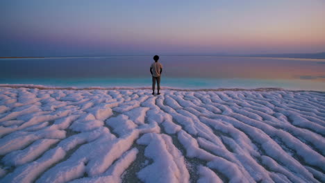 man on a salt flat at sunset