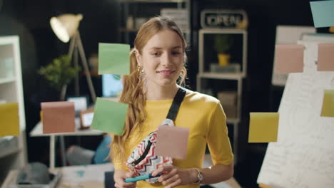 mujer de negocios moderna sonriendo cerca del tablero de trabajo con pegatinas en el interior