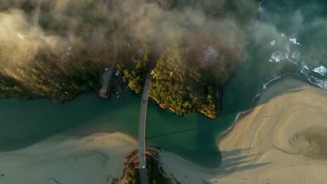 overhead drone shot of cars driving across a cinematic bridge on california's coast