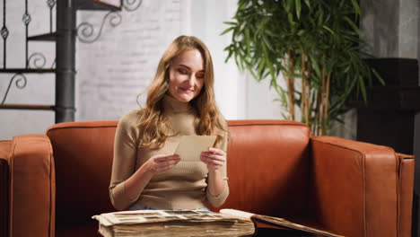 Smiling-woman-looks-at-family-old-picture-in-photo-album