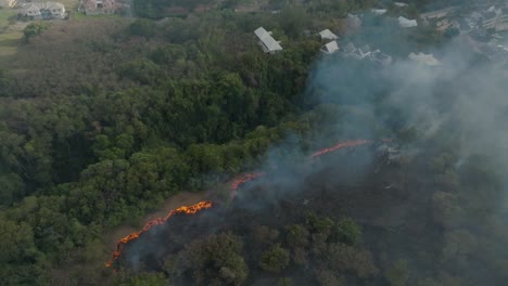 Drone-shot-of-smoke-from-a-forest-fire-on-an-island-with-the-flames-visible