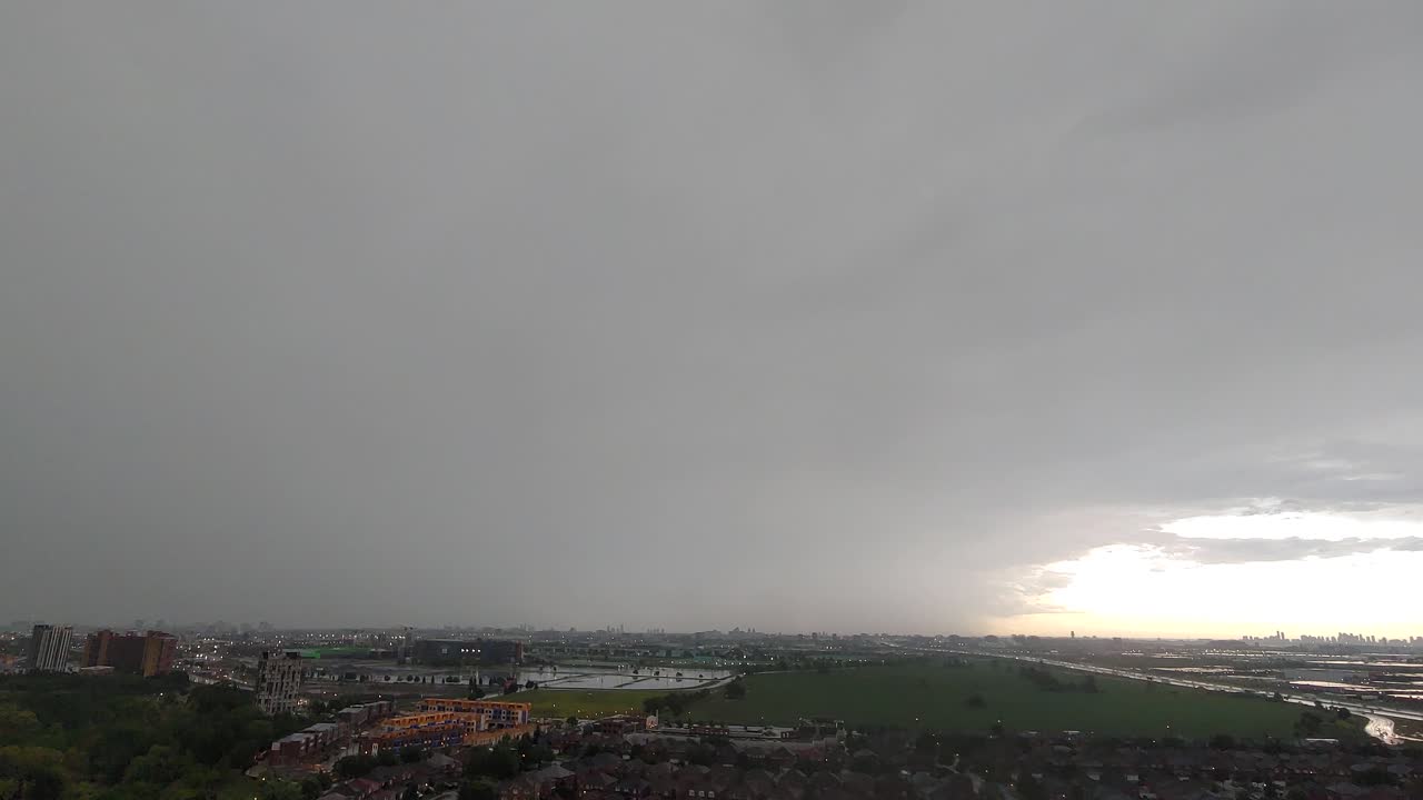 lapso de tiempo de día lluvioso, cielo nublado, relámpagos sobre la vista de la ciudad y el prado verde