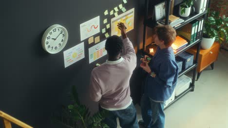 two colleagues discussing business strategy and printed chart in office