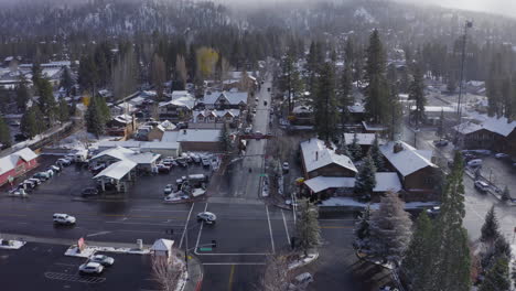 aerial over snow covered buildings in town center of big bear during winter, drone christmas town