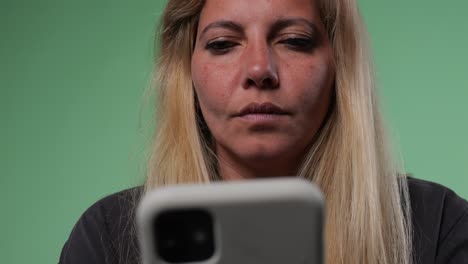 mujer rubia escribiendo un mensaje de texto en el teléfono inteligente mirando a través de aplicaciones pantalla verde tecla de croma