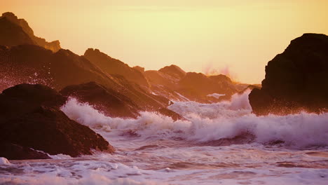 ocean waves crashing on the rocks in the beach during sunset