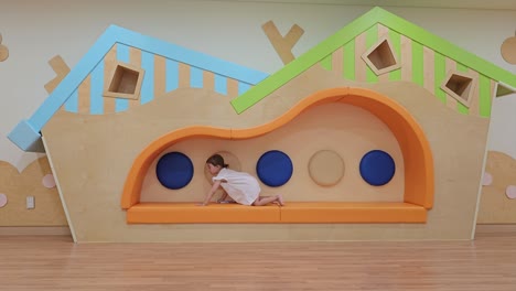 Cute-Little-Girl-Crawling-On-Bench-At-Indoor-Play-Center---wide