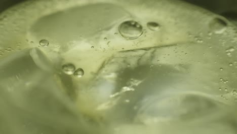 an ice cube falling into ginger beer in slow motion