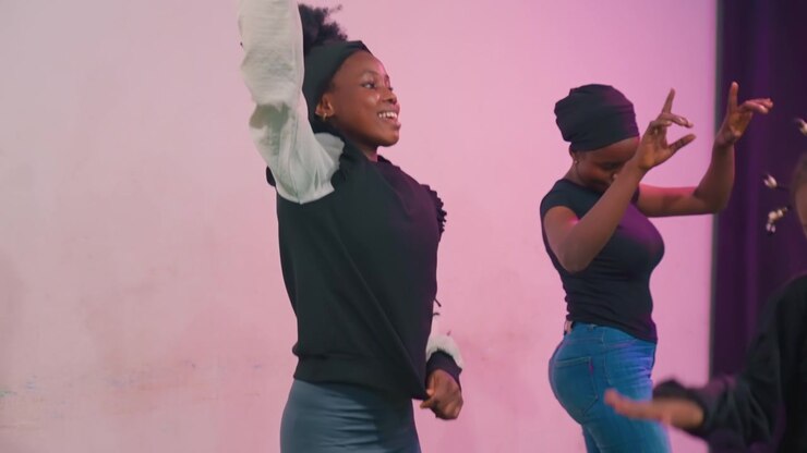 Black mother and child performing expressive gesture dance, animated hand motions and callandresponse leadership, rhythmic counting and joyful faces, pink lighting and indoor studio atmosphere, casual
