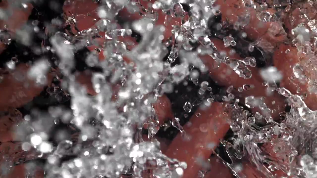 Acqua che schizza su salsicce rosse al rallentatore
