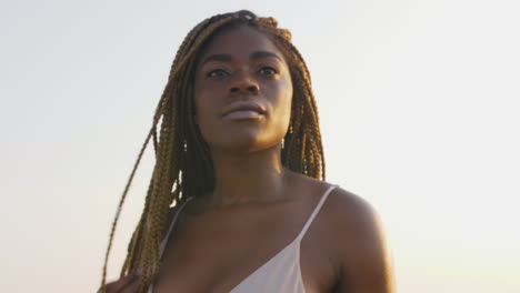 Modelo-De-Bikini-Africano-Con-Trenzas-Posando-En-La-Playa-Durante-Una-Puesta-De-Sol