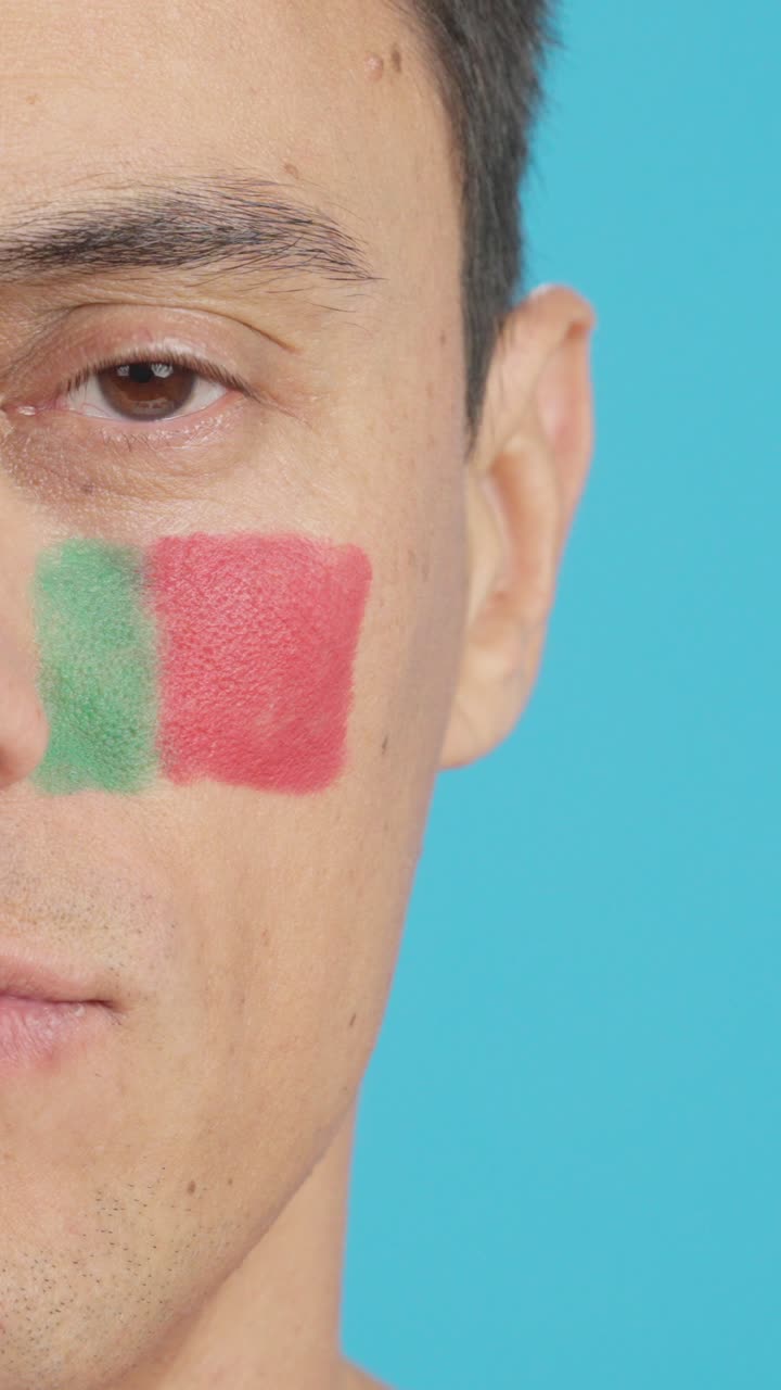 Man with a portuguese flag painted on the face smiling