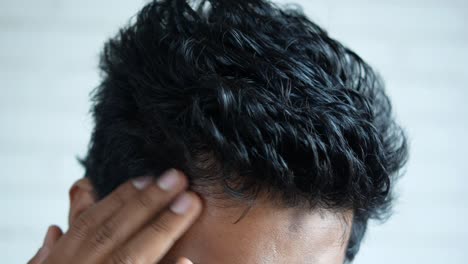 close-up of a man's head with curly black hair and potential hair loss