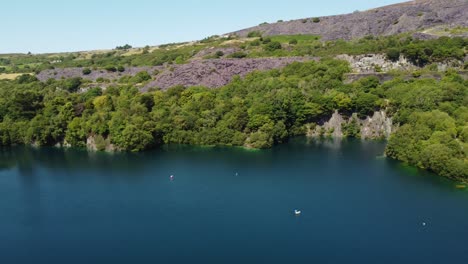 aerial panning view dorothea slate mining quarry woodland in snowdonia valley with gorgeous shimmering blue lake