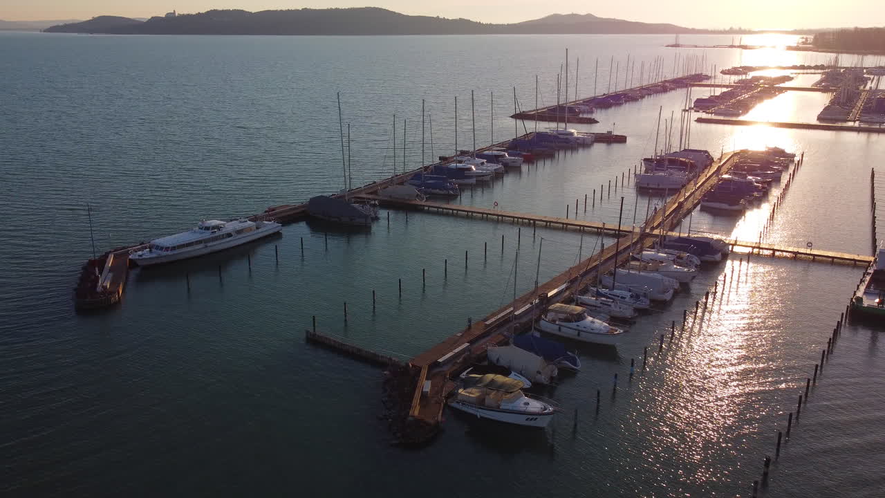 Top-down aerial of marina piers at Balatonfured in Hungary lit by warm low sunset glow