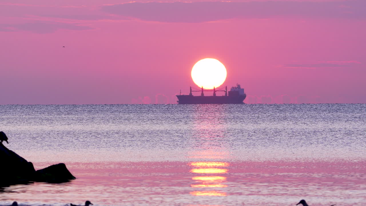 Golden light breaking through clouds over the calm sea in Orłowo at dawn