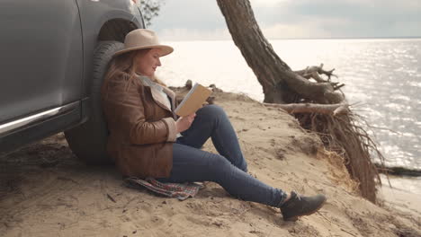 Hermosa-Mujer-Pelirroja-Leyendo-Un-Libro-Junto-A-Un-Lago