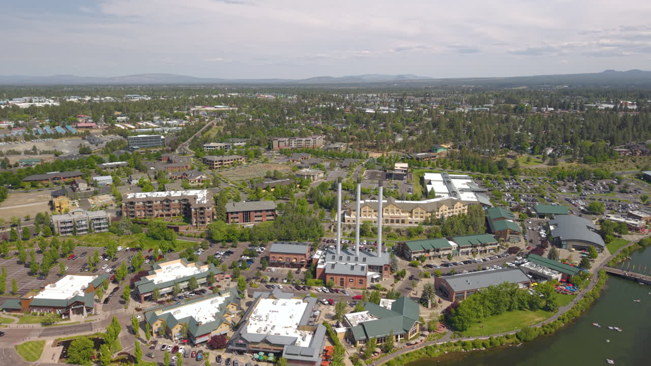 Drone flight over Deschutes River in Bend. People tubing and surfing on the river. Drone backwards 4k shot.
